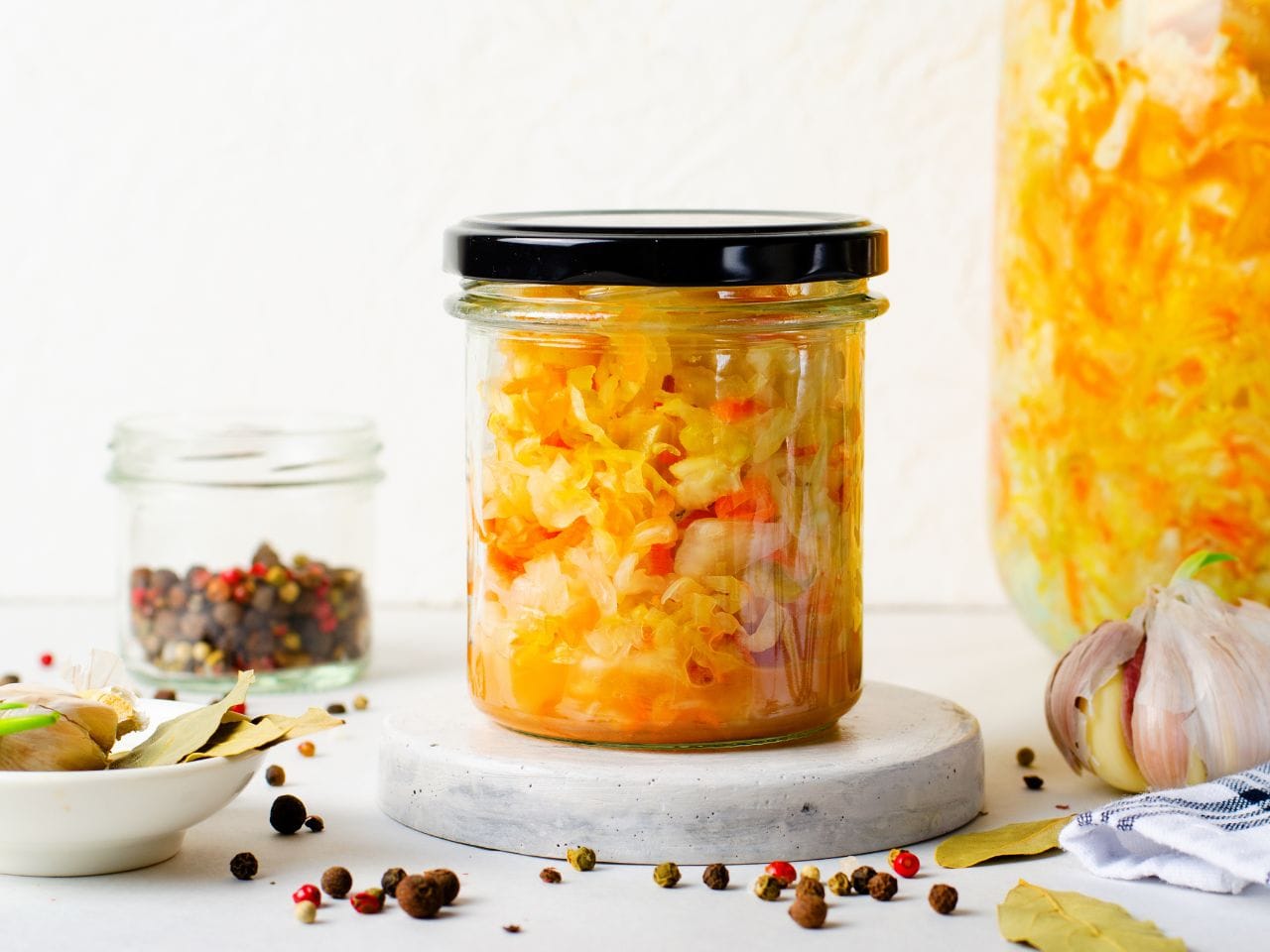 En arborist sitter högst upp i ett träd och sågar av toppen. BLå himmel i bakgrunden.