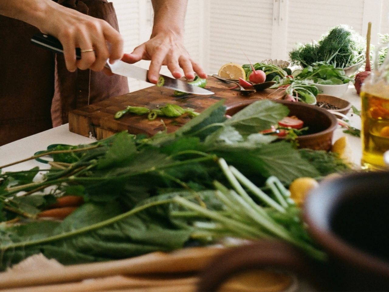 I bakgrunden står en vit get och i förgrunden häller någon upp mjölk i en behållare. 