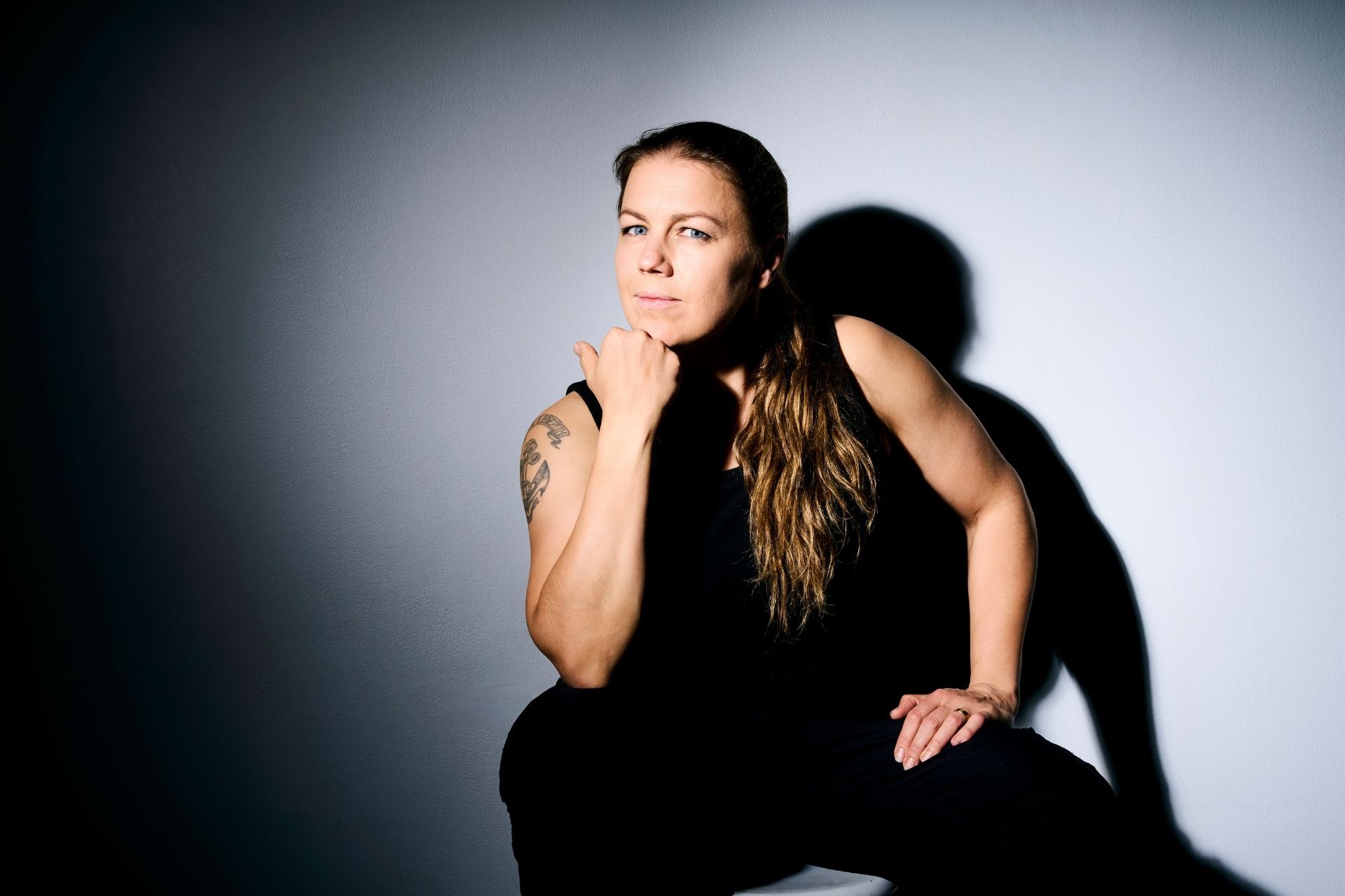 Lena W Tatuerad kvinna i svarta kläder tittar in i kameran.